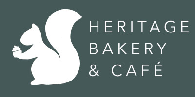 Heritage bakery white logo of a squirrel with heritage bakery and cafe to the right, all on a blue/grey background  